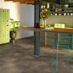 Dark grey stone-effect vinyl tiles in an industrial-style kitchen with green tiled shelving