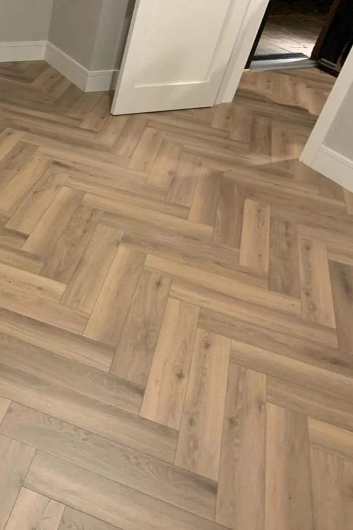 Light oak herringbone laminate flooring in a bright hallway