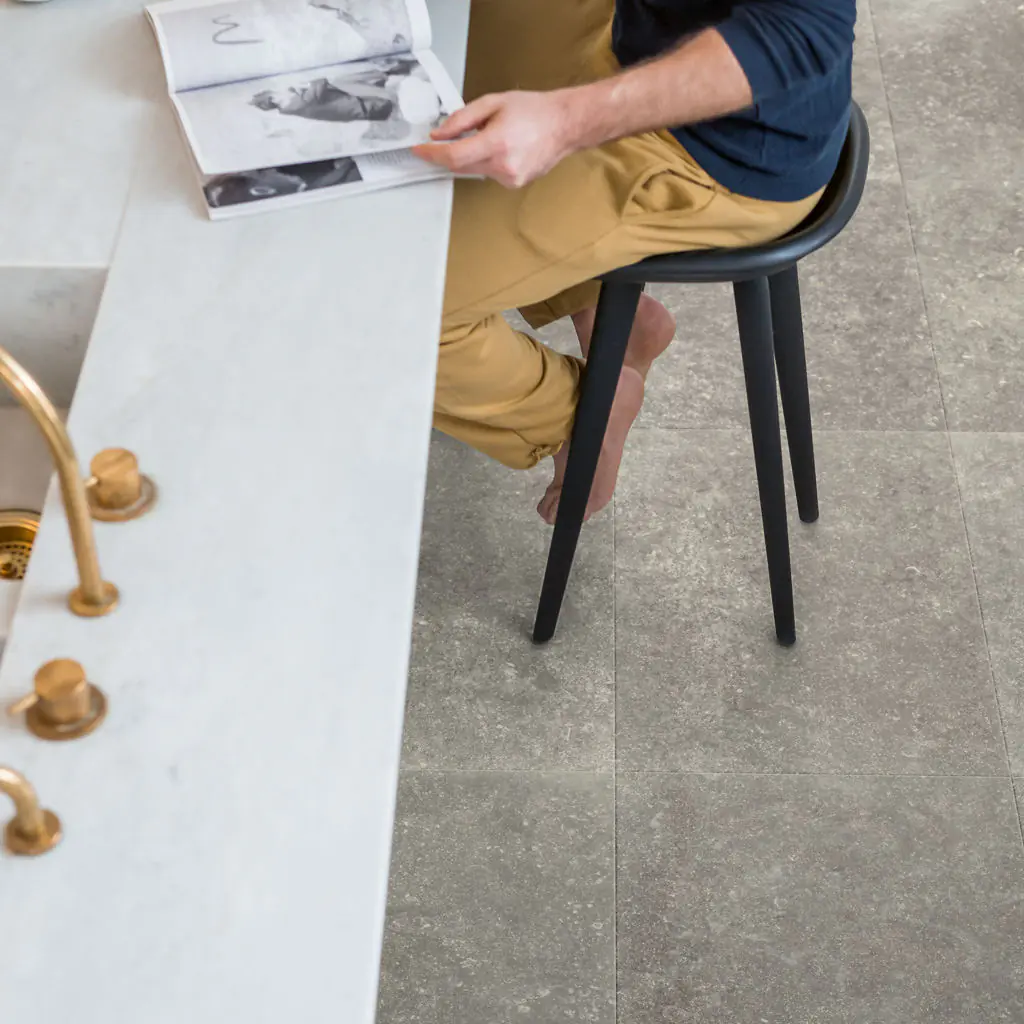 Grey stone tile effect laminate flooring in modern kitchen with bar stool