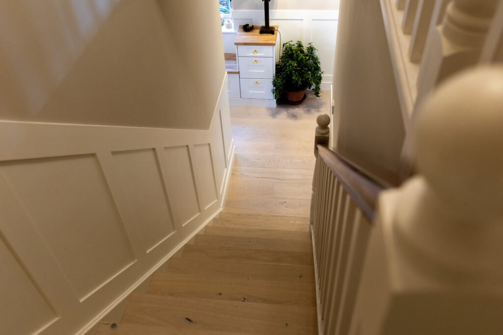 Natural wood staircase treads with white risers and wooden handrail - Royal Flooring Company